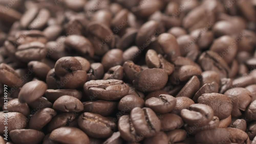 Slow motion closeup coffee beans falling into bowl