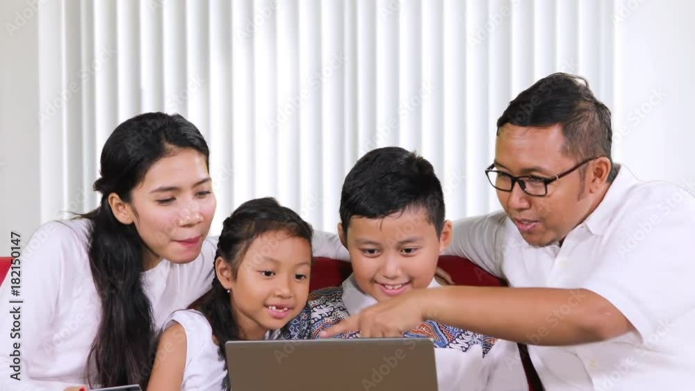 Happy family on shopping together with a laptop and credit card while sitting on the sofa in the living room at home Happy family on shopping together with a laptop and credit card while sitting on the sofa in the living room at home