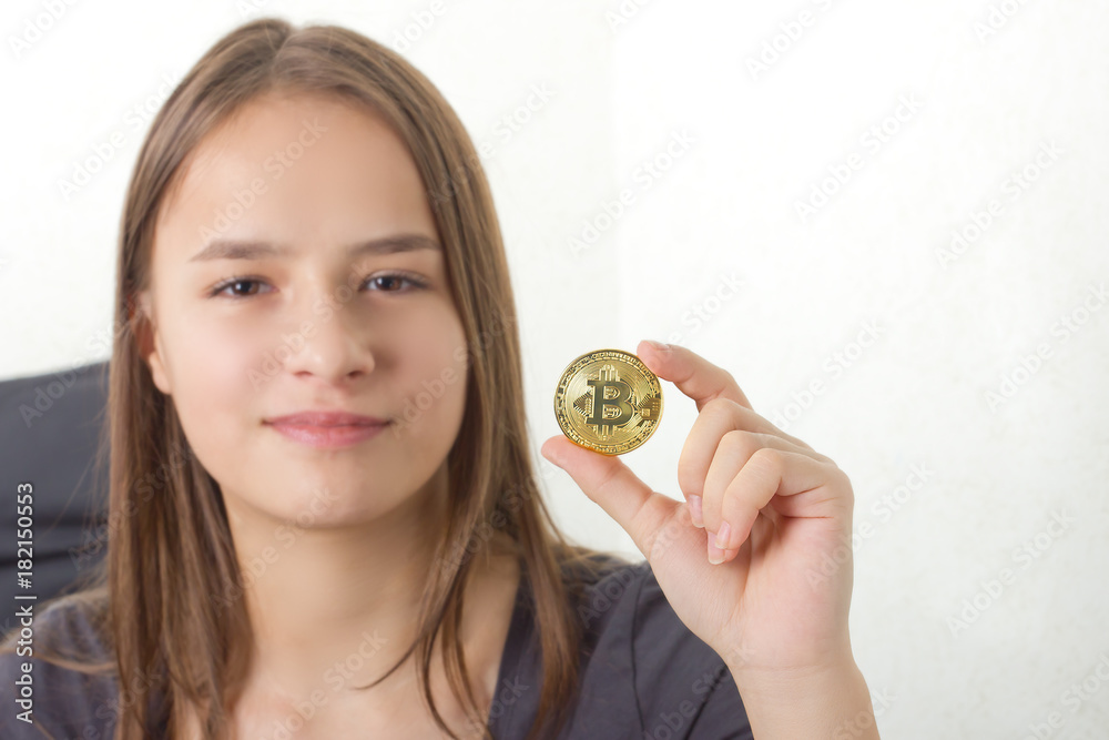 Young girl sitting on bed,holding a bitcoin Young girl sitting on bed,holding a bitcoin
