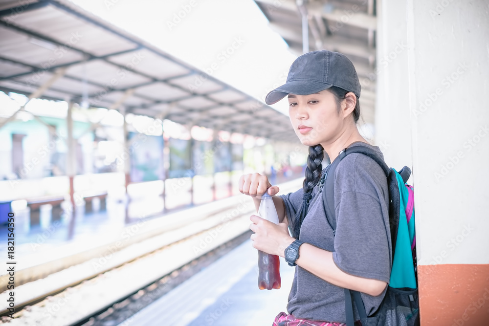 young woman traveler wearing backpack waiting railway at train station, Summer holiday and travel concept young woman traveler wearing backpack waiting railway at train station, Summer holiday and travel concept