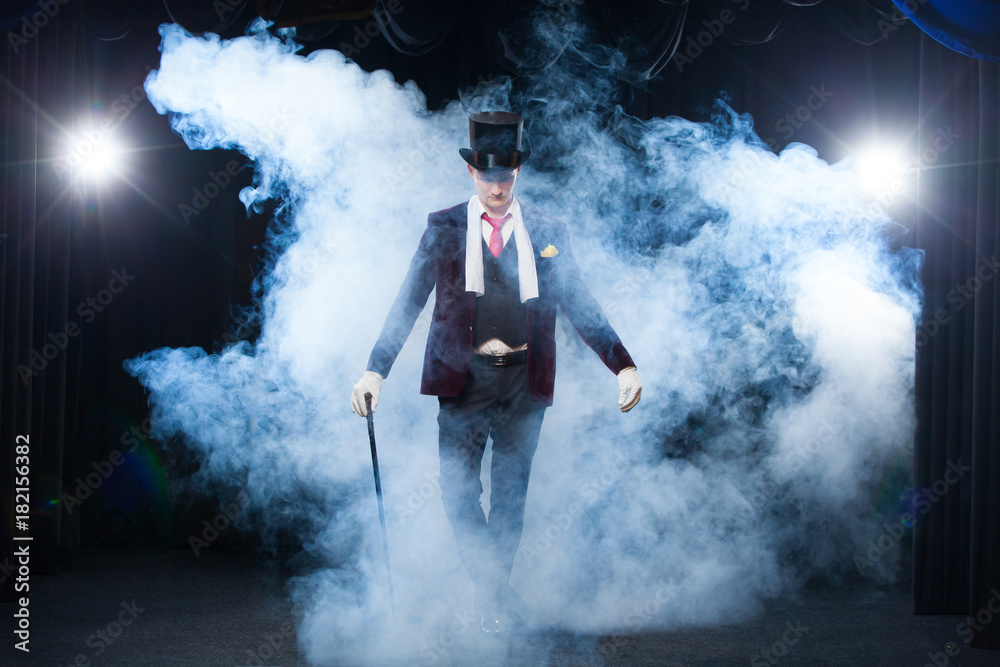 Magician, Juggler man, Funny person, Black magic, Illusion standing on the stage with a cane of beautiful light. shrouded in a beautiful mysterious smoke