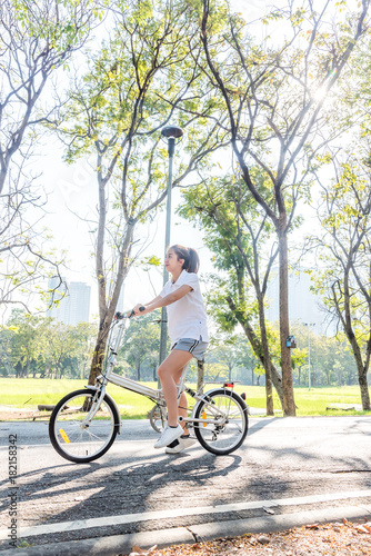 Portrait of happy beautiful smiling young woman on bicycle in the park