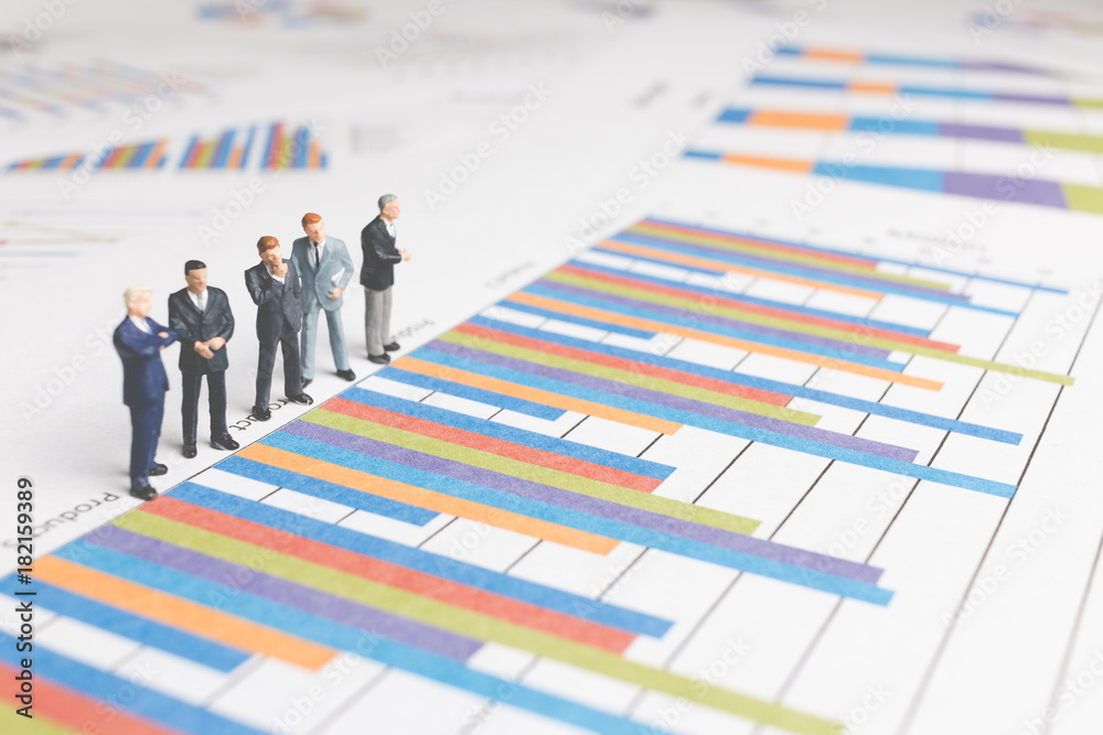 Miniature People : Businessman standing on a Paper graph chart ,Developing a teamwork concept Miniature People : Businessman standing on a Paper graph chart ,Developing a teamwork concept