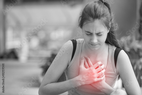 Cute teenage girl with gesture cardiac massage or clutching her chest after acute pain heart attack. Young woman having chest pain or Heart attack symptom. healthcare and lifestyle concept
