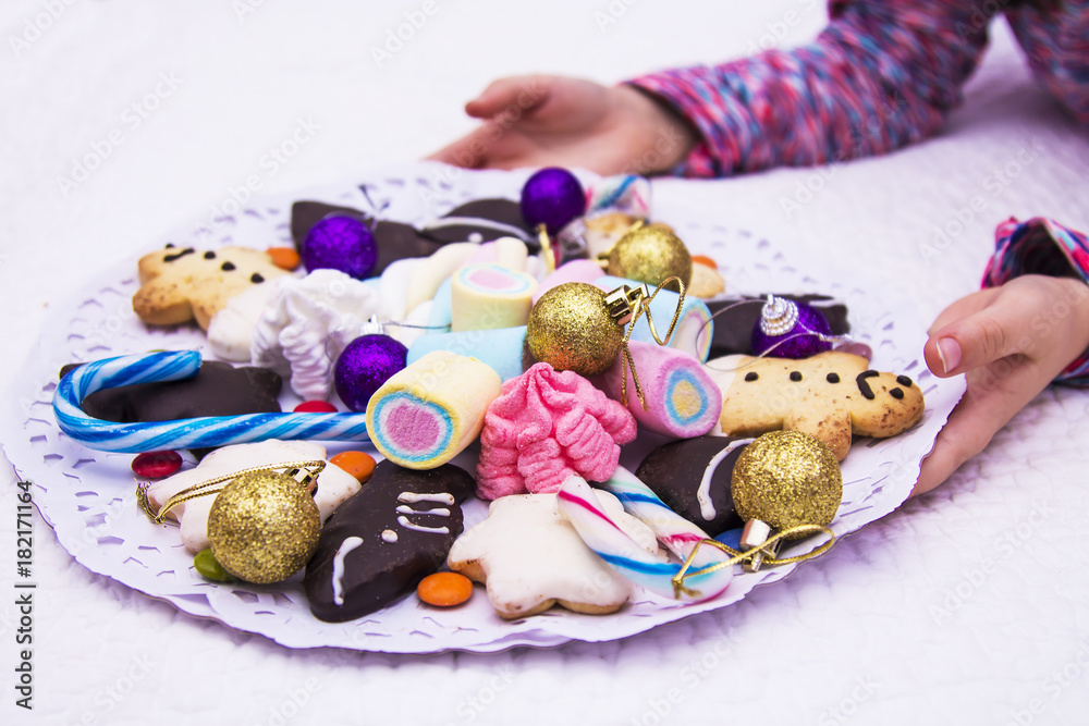 girl holding tray with assorted christmas cookies and marshmallows