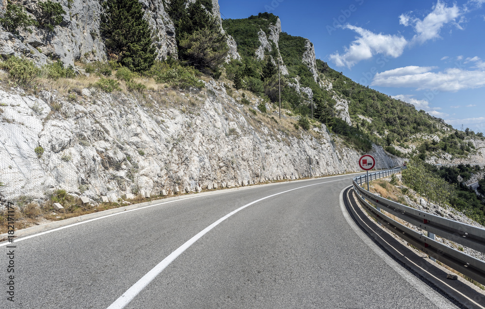 Fototapeta premium Country road through the rocky mountains and forest.