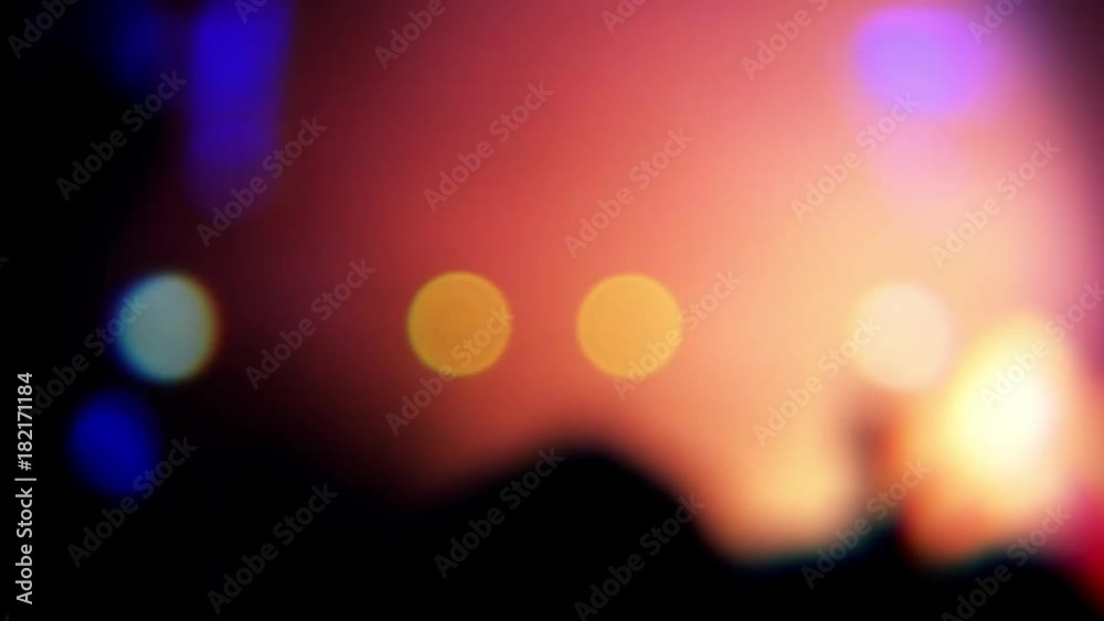 Blurred people clapping hands at music concert. Vibrant and colorful light show.