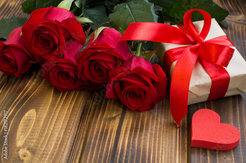 Red roses,gift box and heart on the wooden background