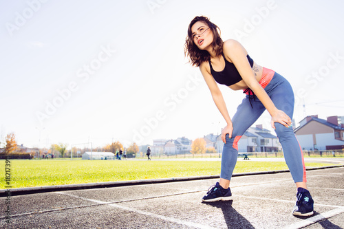 Young sporty woman taking breath after jogging on the track in stadium.