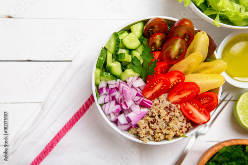 Vegetarian Buddha salad bowl with red onions mixed cheery tomatoes, cucumbers and quinoa with an oil and lime on the side. Top horizontal view copy space.