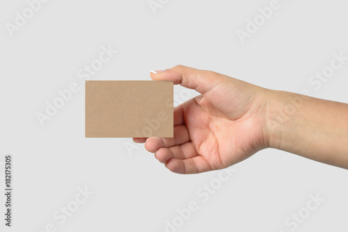 Mockup of female hand holding a Kraft Paper Business Card isolated on light grey background. Size 85 × 55 mm.