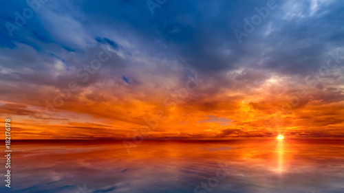 Beautiful cloudscape and sunset breaking through cloud over lake reflection. god rays, also called crepuscular rays, streaming through gaps in clouds. © Quardia Inc.