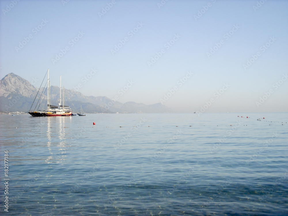 Obraz premium Kemer Antalya bella vista sul mare. Spiaggia Kemer Antalya con sabbia e montagne, il mare con la nave. Bellissimo porto vicino alla spiaggia di sabbia.