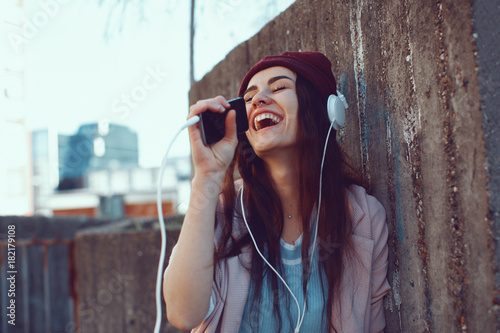 Young urban woman listens to music via headphones and smartphones