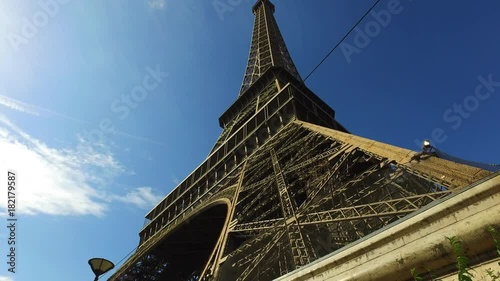 A wide moving shot of the Eiffel Tower in Paris in front of the blue sky. photo