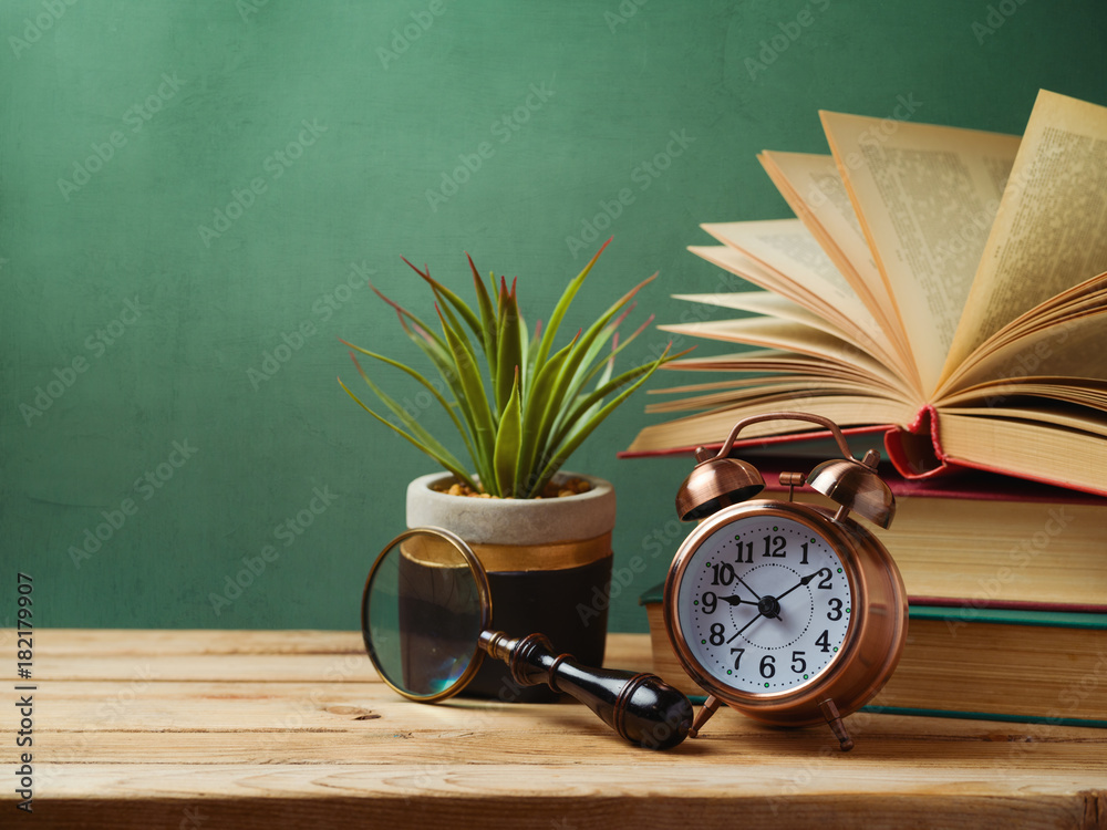Alarm clock, books and plant on wooden table Alarm clock, books and plant on wooden table