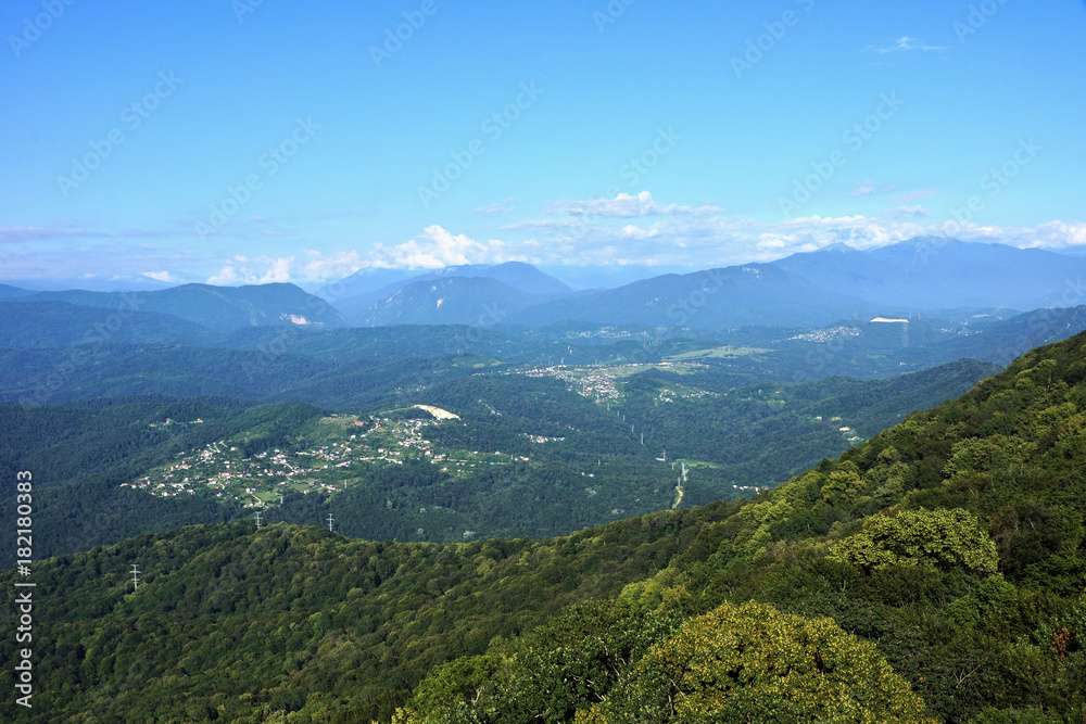 Panorama of the mountains in the area of Krasnaya Polyana/Panorama of Sochi in the Krasnaya Polyana area. There are mountains, clouds, air haze, vegetation. Sochi, Russia, mountain landscape