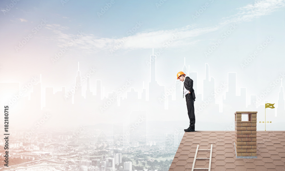 Engineer man standing on roof and looking down. Mixed media Engineer man standing on roof and looking down. Mixed media