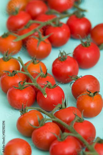 Closeup on fresh organic cherry tomatoes on turquoise wooden background.