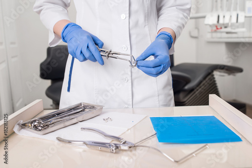Dentist with gloved hands is working with dental equipment in dental office. Close-up