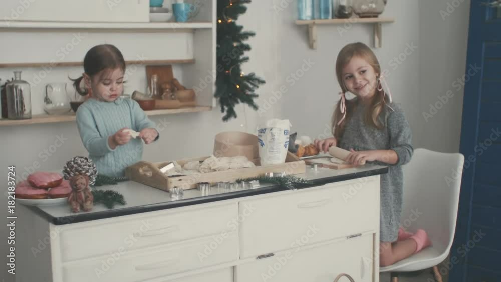 little girls make dough, bake cookies in the kitchen