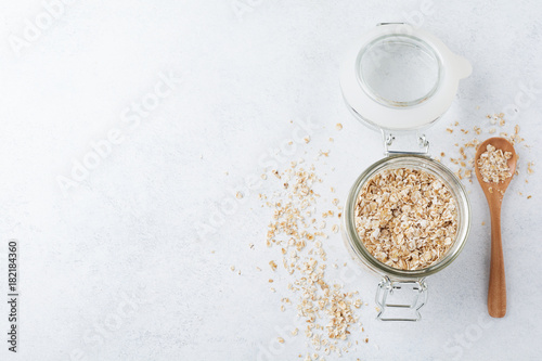 Raw oat flakes in a glass jar on a light background.Oatmeal. Selective focus.Top view. Copy space.