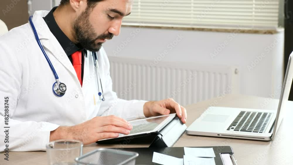 Doctor in his office looking searching on digital tablet Doctor in his office looking searching on digital tablet