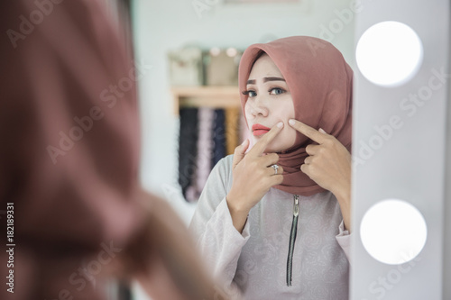 woman squeezing her pimple photo