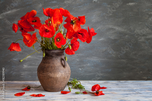 Fototapeta Naklejka Na Ścianę i Meble -  Still life in a rustic style: an old crock and a bouquet of red poppies on a wooden table