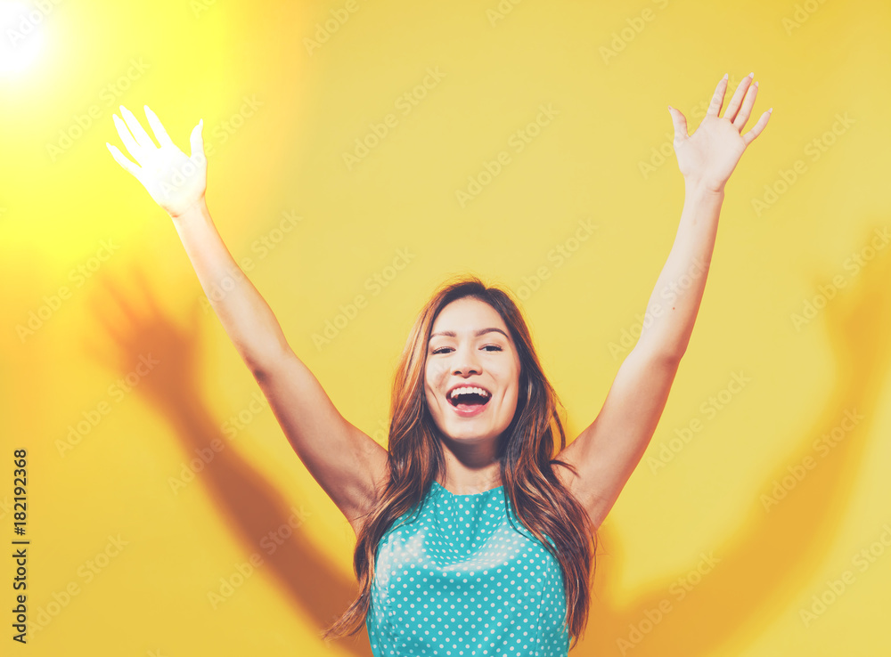 Happy young woman raising her arms on a solid background Happy young woman raising her arms on a solid background