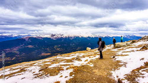Three people enjoying the view on top of The Whistlers mountain in Jasper National park in the Canadian Rockies