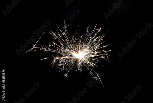 Burning sparkler on black background.