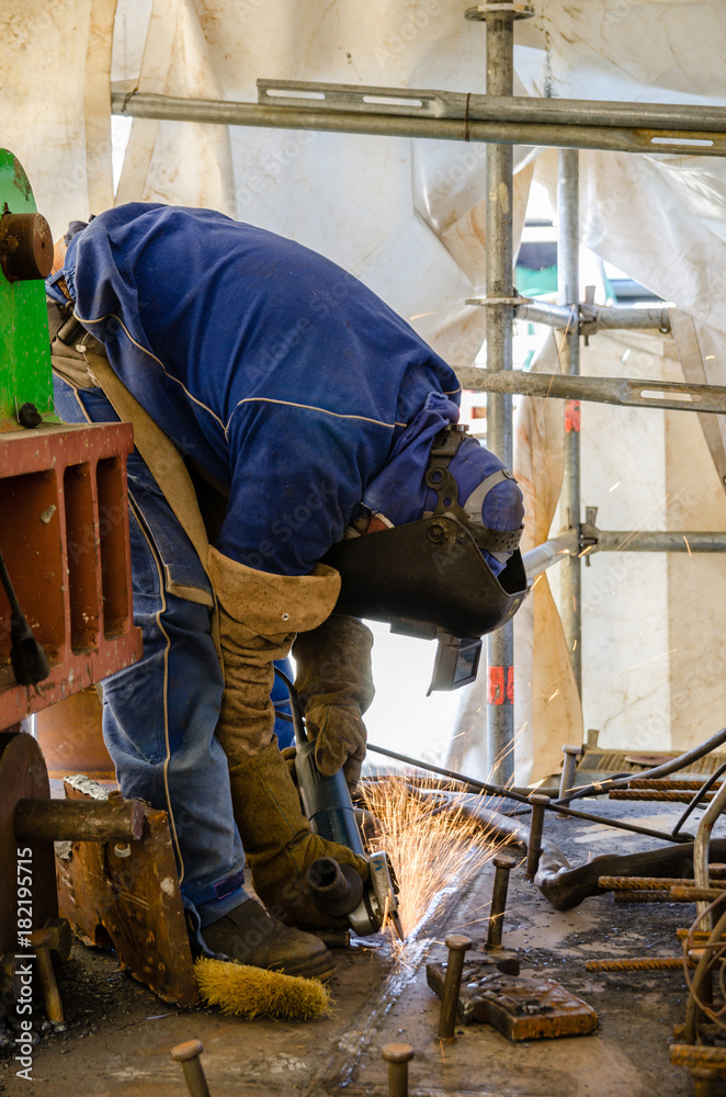 Welding worker with a radial saw on a construction site Welding worker with a radial saw on a construction site