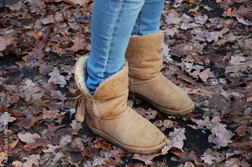 Legs of a girl, shod in brown uggs in autumn.