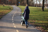 A woman with a stroller walks in an autumn park.