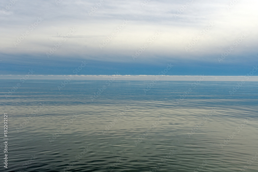 Obraz premium Calm Waters and Distant Clouds on a Lake Shore