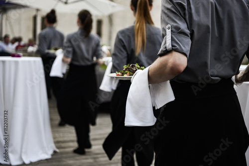 Waiters carrying plates with meat dish on some festive event photo