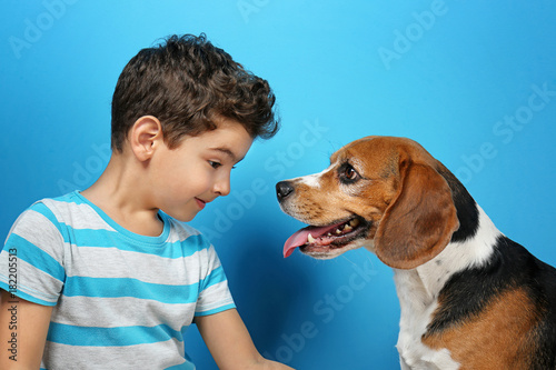 Cute boy with dog on color background