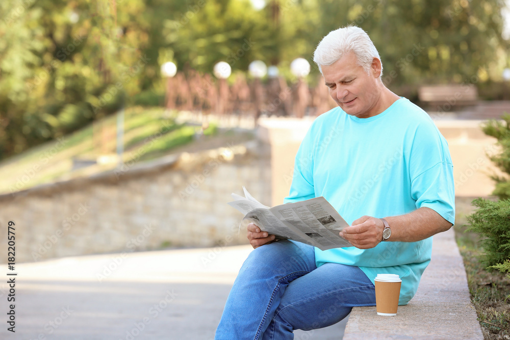 Obraz premium Handsome mature man with newspaper in park