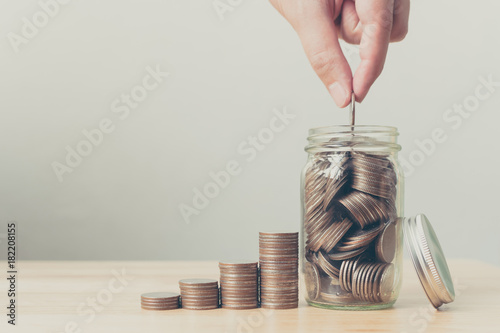 Quadro em tela Hand of male or female putting coins in jar with money stack step growing growth