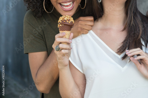 Girl trying to bite other friend's ice cream cone
