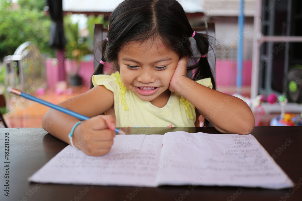 Asian child girl use Pencil write letters on the book. Asian child girl use Pencil write letters on the book.