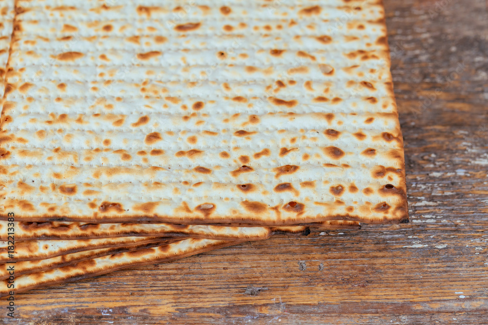 Jewish kosher matzah closeup on paper on a wooden table. horizontal view Jewish kosher matzah closeup on paper on a wooden table. horizontal view