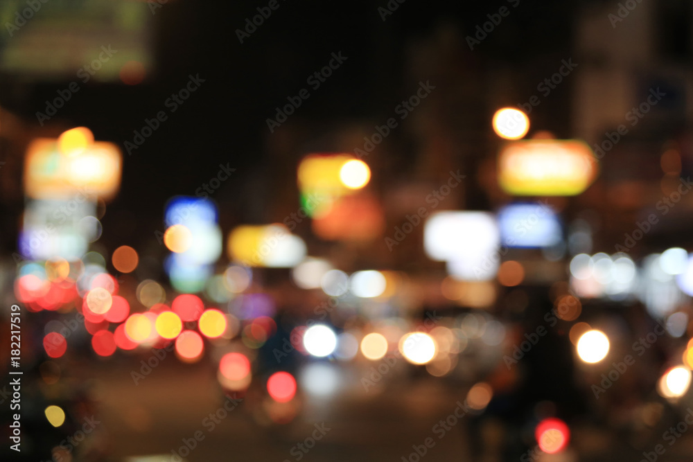 Blurry background of road with roaming cars at night.