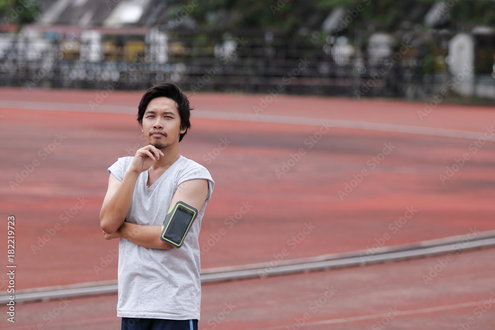 Portrait of young fitness Asian man  looking at camera and standing on track in the stadium