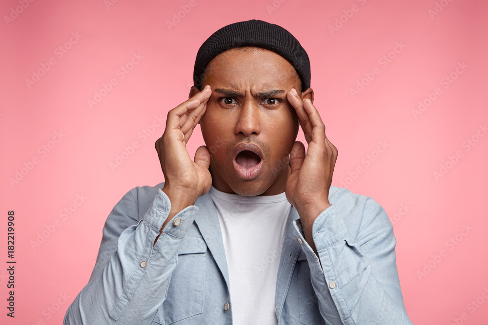 Horrified stunned mixed race male openes mouth widely, can`t undertand what happend, has puzzled expression, looks scaring, isolated over pink studio background. Amazed multiethnic fashionable man Horrified stunned mixed race male openes mouth widely, can`t undertand what happend, has puzzled expression, looks scaring, isolated over pink studio background. Amazed multiethnic fashionable man