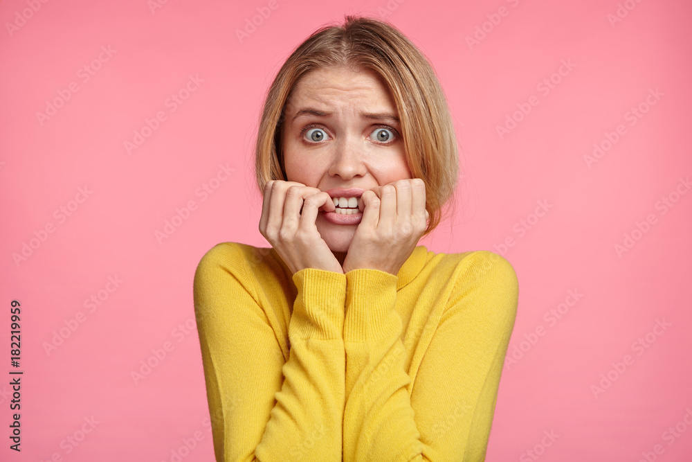 Worried female looks nervously, bites finger nails, watches moving strilling film, anticipates what end will be. Nervous excited young woman worries before job interview, wants to show her best Worried female looks nervously, bites finger nails, watches moving strilling film, anticipates what end will be. Nervous excited young woman worries before job interview, wants to show her best