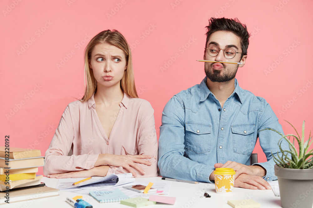 Unhappy puzzled young people collborate together for making project, have not enough information, feel tired and overworked, sit at coworking space over pink background. Upset students working Unhappy puzzled young people collborate together for making project, have not enough information, feel tired and overworked, sit at coworking space over pink background. Upset students working