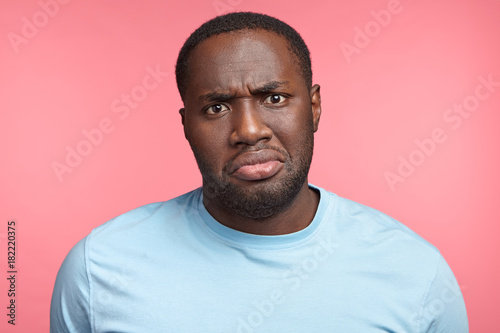 Portrait of discontent black male frowns face in displeasure being unhappy to recieve bad news or after divorce with wife, feels lonely and frustrated, has troubles in life, upset, offended.