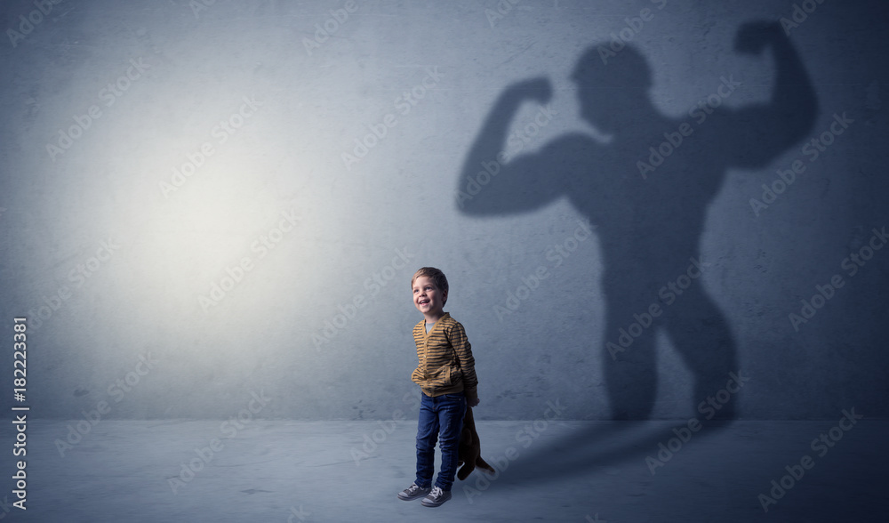 Muscleman shadow behind waggish little boy Muscleman shadow behind waggish little boy